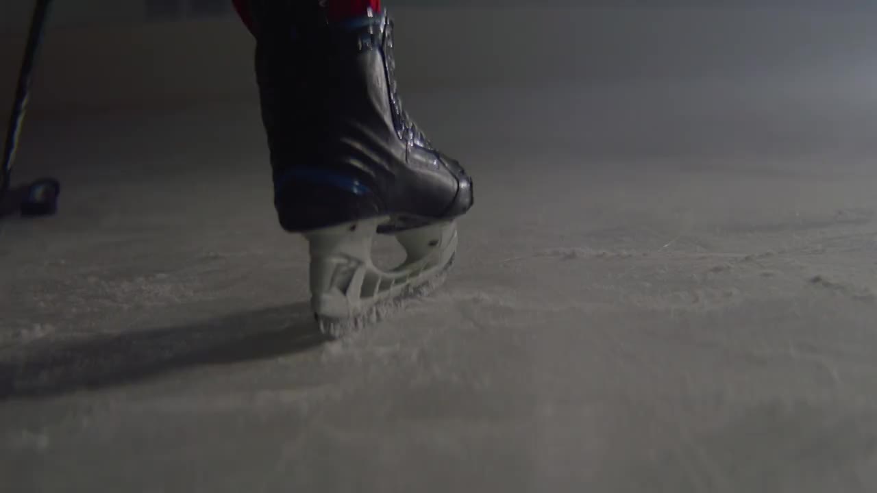 冰球运动员领先冰球与棒子在冰上竞技场特写视频购买