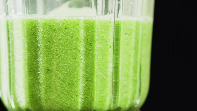 绿色奶昔混合在搅拌机里，特写。健康饮食的概念。视频素材