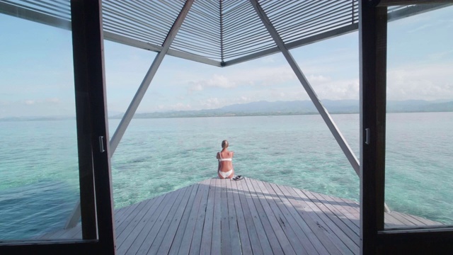 一个穿着比基尼的女人在度假的热带岛屿酒店度假村的对称场景。视频素材