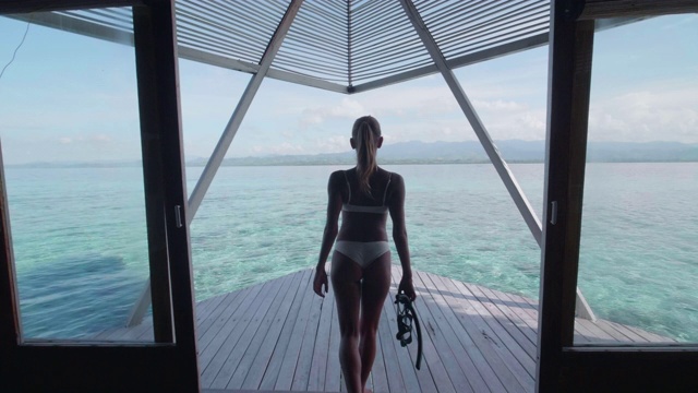 一个穿着比基尼的女人在度假的热带岛屿酒店度假村的对称场景。视频素材