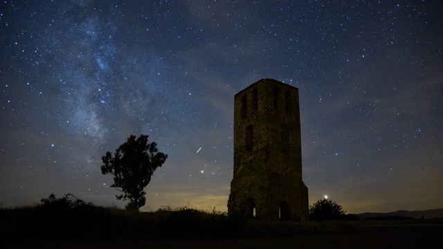 划过夜空的银河和一座古老的城堡塔楼视频素材