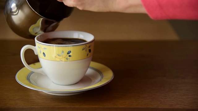 将新煮好的黑咖啡倒入陶瓷杯中。视频素材