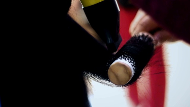 一个不知名的理发师在美发沙龙吹干年轻女子的头发的实时视频视频素材