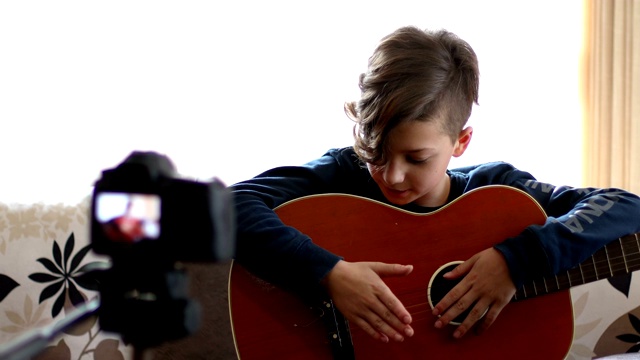 快乐的孩子，弹着原声吉他，看着镜头视频下载