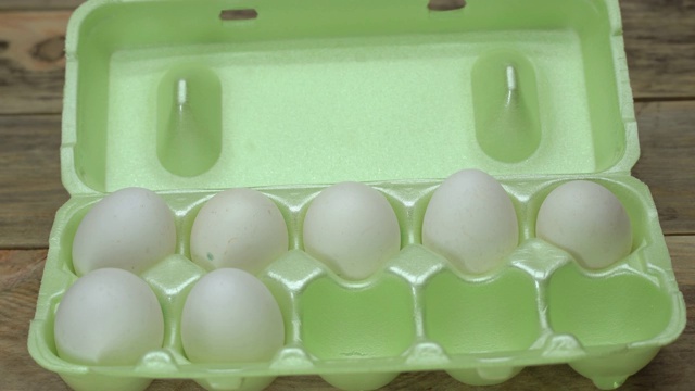 一个女人的手从托盘里拿了一个白色的鸡蛋。视频下载