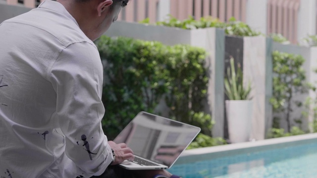 一个亚洲人在家里用笔记本电脑工作。视频素材