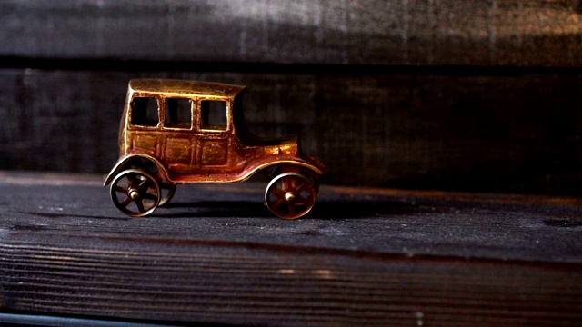 木制背景上的金色复古汽车雕像。极简主义。汽车保险的概念，买卖汽车。车辆的维修和保养。视频下载