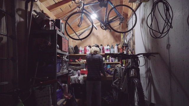 一个年轻人在他的车库车间独自修理一辆自行车，社交距离。视频下载