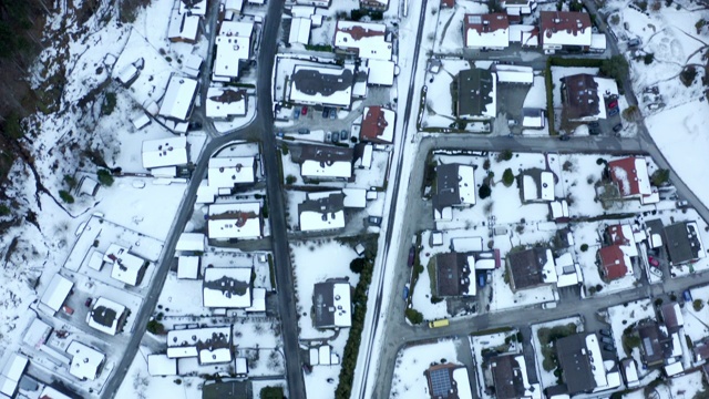 空中拍摄的街道在房屋在雪覆盖的城镇，无人机飞在居民区在冬季-埃尔福特，德国视频下载