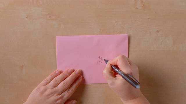 女性的手写在一个粉红色的信封上视频素材