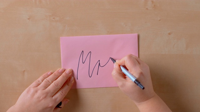 女性的手在粉色信封的背面写着“夫人”视频素材