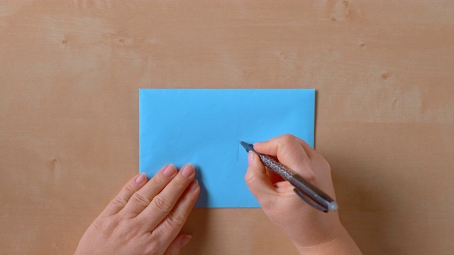 女性的手写在一个蓝色的信封上视频素材