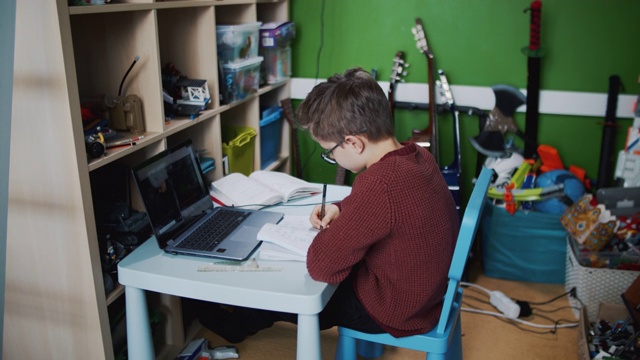 小男孩在他的房间里参加在线学校的课程。视频下载