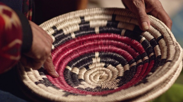 一位60多岁的印第安(纳瓦霍)妇女在触摸一个编织的纳瓦霍篮子时谈论它视频下载