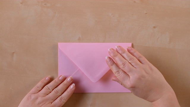 SLO MO LD手打开一个粉红色的信封，并拿出一张纸视频素材