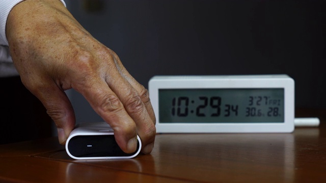 老人用手按下PM2.5检测仪的开启按钮，监控空气质量视频素材