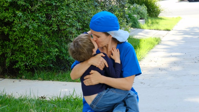 小男孩拥抱他的母亲，他的母亲是一名医护人员，他已经好几个星期没有见到她了，因为她因为Covid-19正在忙着治病救人视频下载
