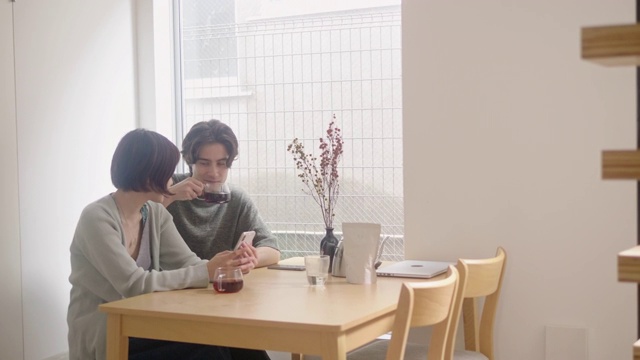 跨种族的年轻夫妇喝早上的咖啡，同时使用智能手机视频素材