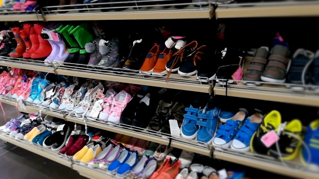 商店里有专为男孩、女孩和儿童设计的鞋柜。儿童鞋，运动鞋和各种颜色的靴子在购物中心或大卖场视频素材