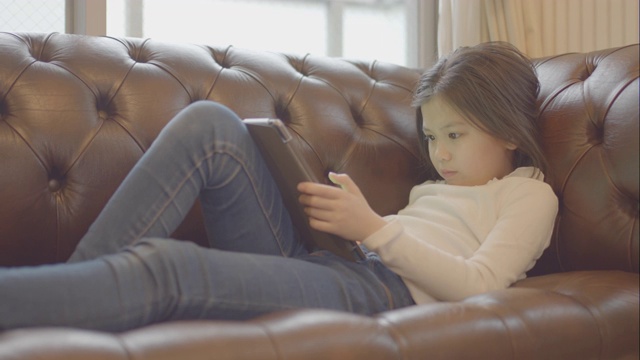 十几岁的女孩在家里用平板电脑看电影。视频下载