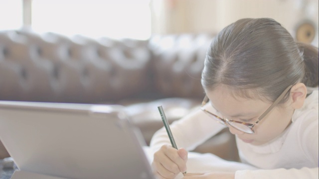一个女孩在家里用平板电脑学习。视频下载