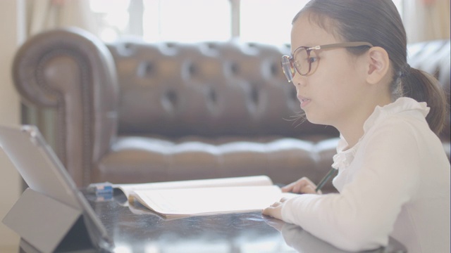 一个女孩在家里用平板电脑学习。视频下载