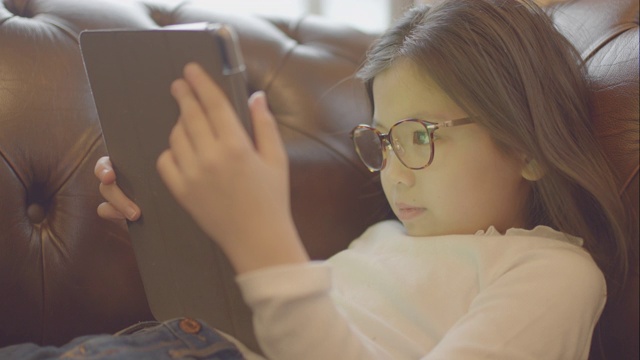 十几岁的女孩在家里用平板电脑看电影。视频下载