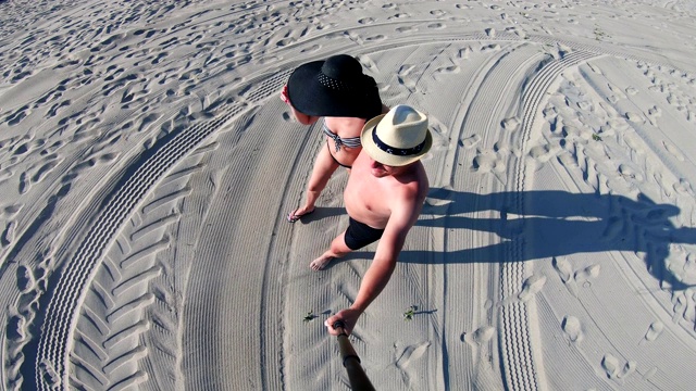 一对兴高采烈的夫妇戴着帽子在空旷的沙滩上散步视频下载