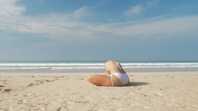 坐在沙滩上的女人身体前倾，然后向后伸展视频下载