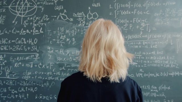 在大学教室里，女科学家拿着公式走到黑板前视频素材