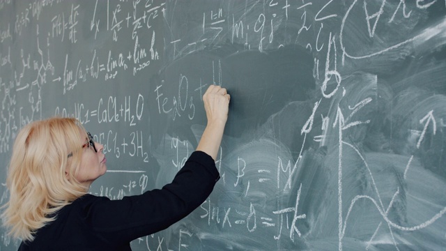 女化学老师严肃的在黑板上写公式的慢镜头视频素材