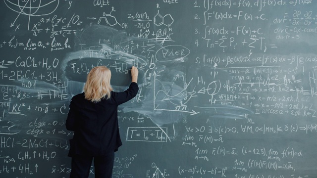 女科学家走到黑板前用粉笔写公式的背影视频素材