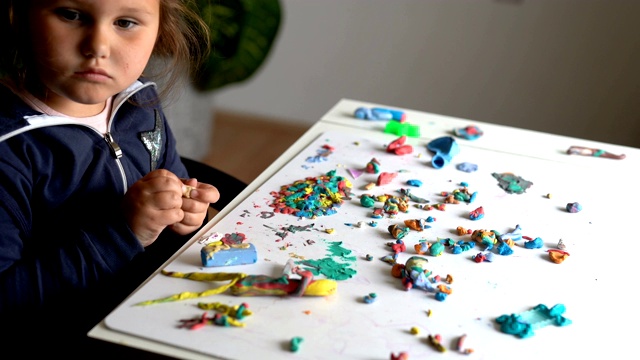 可爱的小女孩在幼儿园玩彩色粘土模型。在家里塑造有创造力的孩子。孩子们玩橡皮泥。4 k视频下载