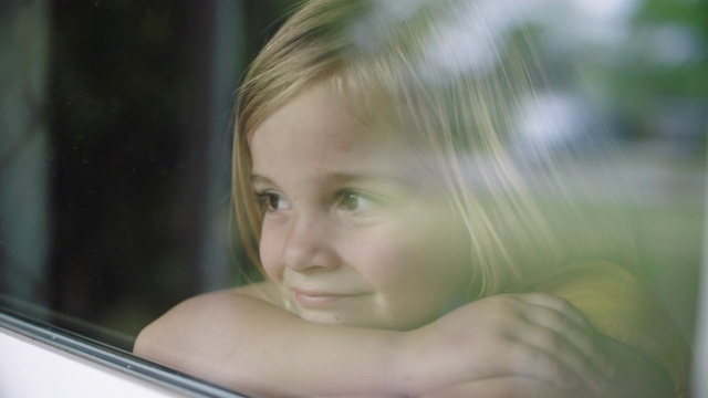 可爱的小女孩微笑着看着窗外视频下载