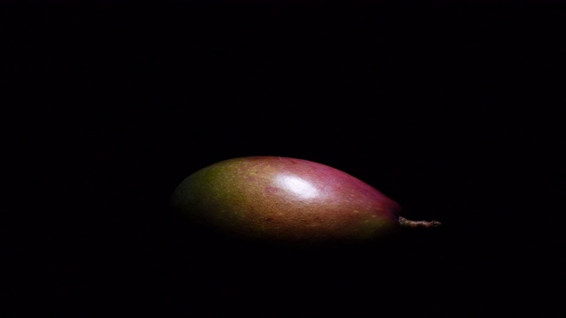 一块芒果在黑色的背景中旋转视频下载