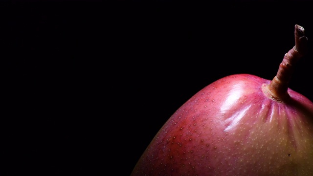 红色的芒果果实在黑色的背景中旋转视频下载