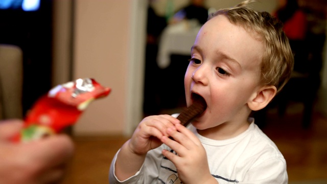 小男婴开心地在家里吃着香蕉形的巧克力蛋糕视频下载