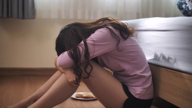 悲伤的亚洲女人抑郁的感觉悲伤躺在卧室的地板上视频下载