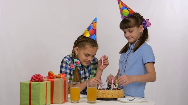 两个女孩在生日蛋糕上插蜡烛视频素材