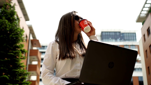 年轻的女商人在户外使用笔记本电脑。视频下载