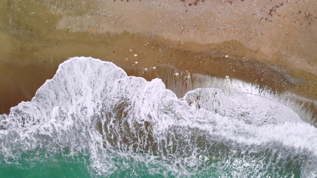 强劲的海浪冲击着荒芜的沙滩，俯视图视频下载