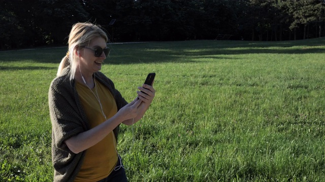 高级妇女在春天的一天在公园里使用电话进行视频通话视频素材