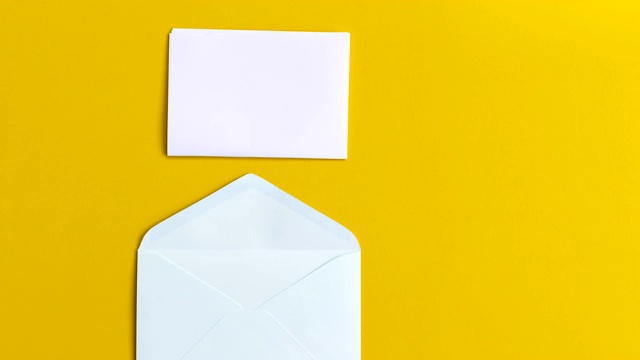 4k停止运动白纸折叠和进入黄色背景的信封，通信镜头视频概念。视频下载