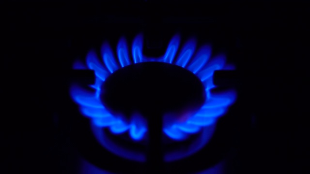 煤气灶在黑暗中打开。炉子在家用煤气中起作用。火焰是蓝色的。视频素材