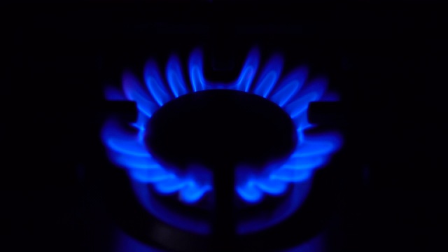 煤气炉在黑暗中熄灭了。炉子在家用煤气中起作用。火焰是蓝色的。视频素材