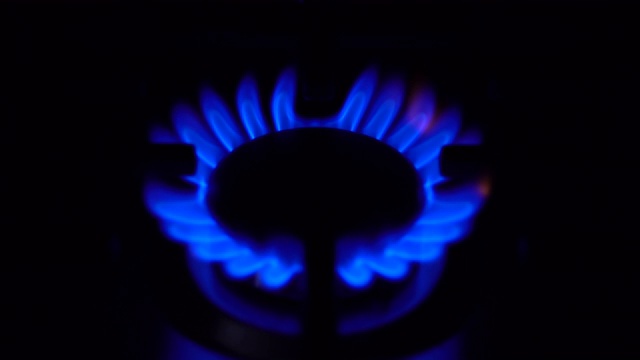煤气灶在黑暗中打开。炉子在家用煤气中起作用。火焰是蓝色的。视频素材
