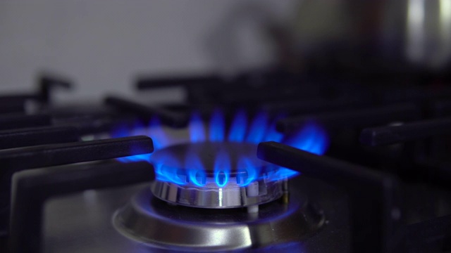 水壶被移出火炉的特写镜头。他们把水壶从火上拿下来，关掉煤气炉。火焰是蓝色的。视频素材