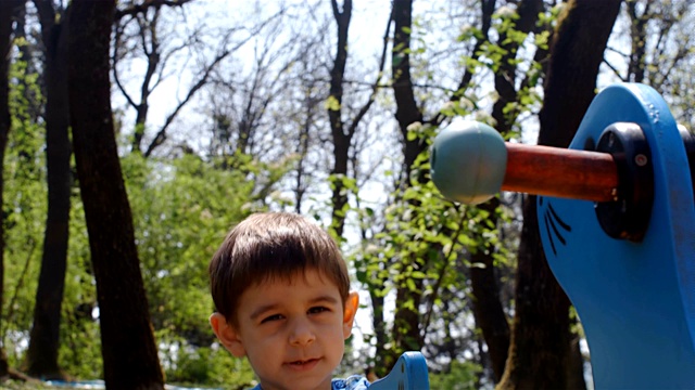 可爱的小男孩在公园玩跷跷板，4k视频下载