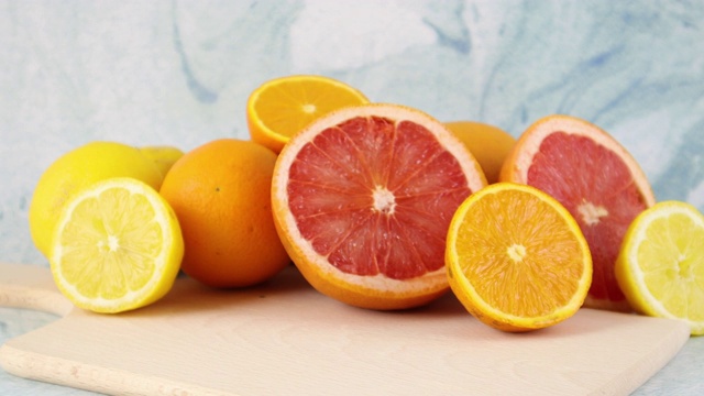 蓝色背景的柑橘类水果-葡萄类水果，柠檬和橙子在切菜板上视频素材
