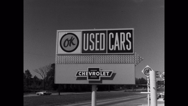 广角镜头的雪佛兰二手车标志与汽车行驶在道路上的背景视频下载